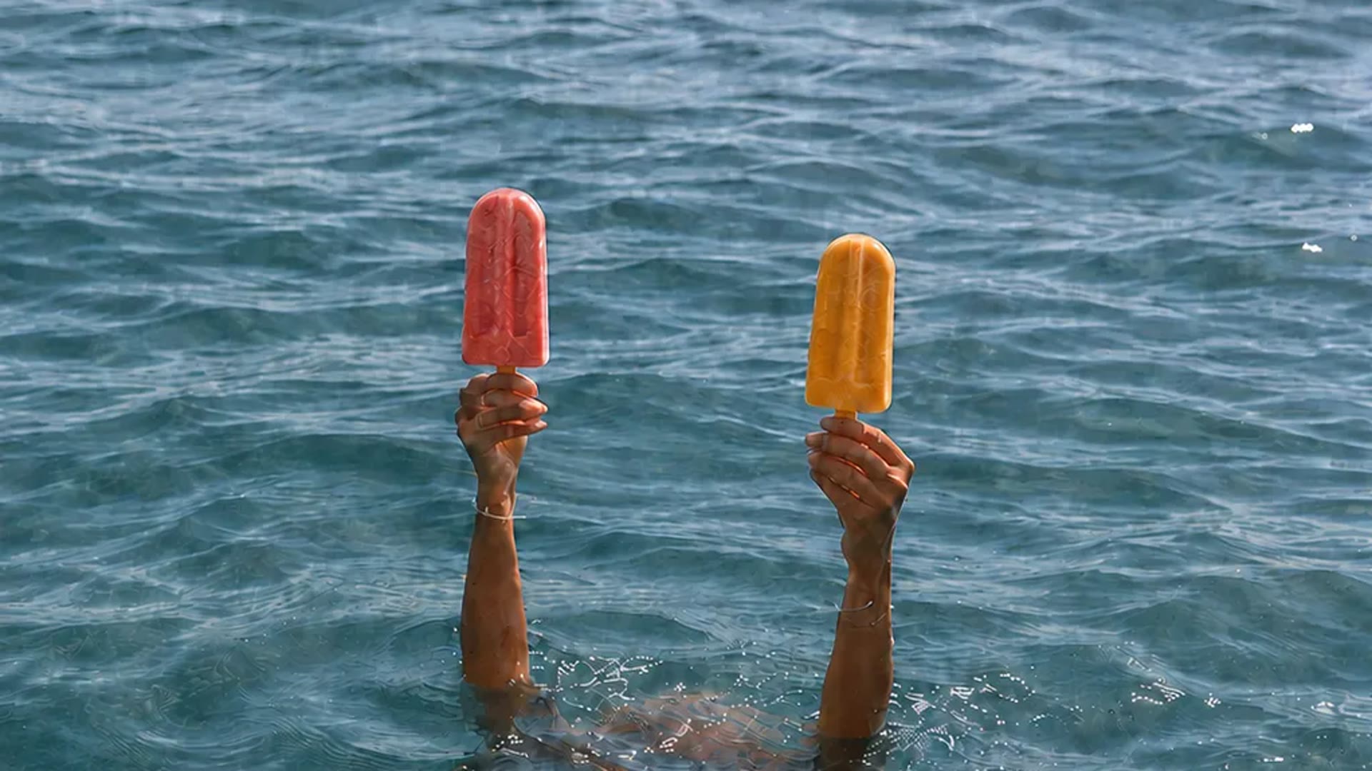 A swimmer holding frozen pops above water