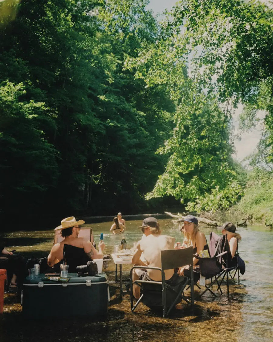 Friends gathered around a table in a shaded creek